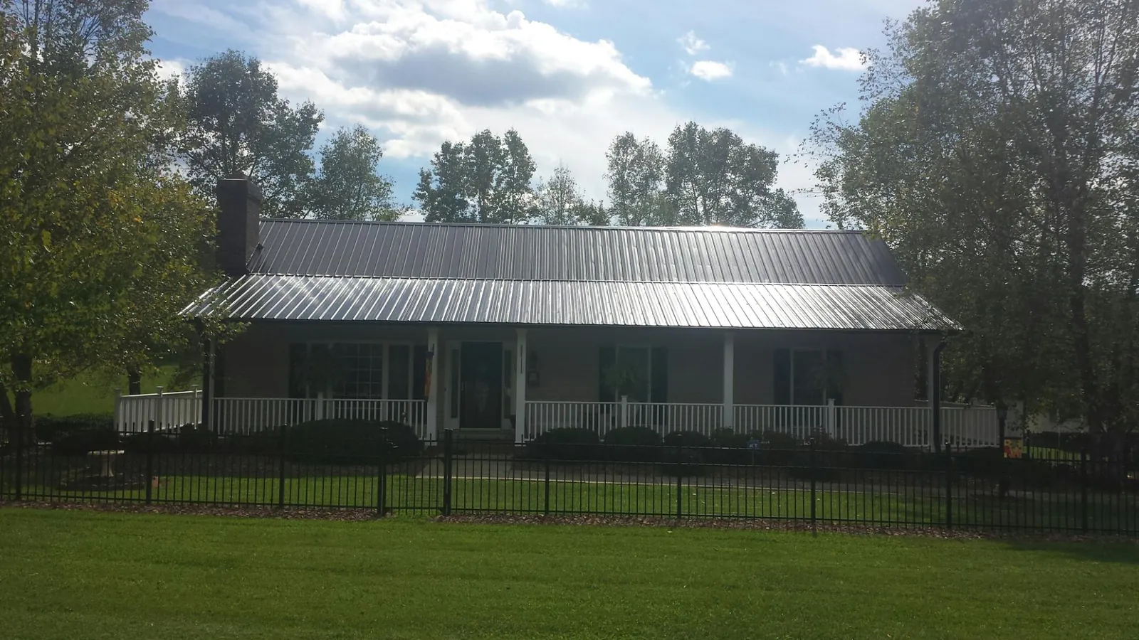 Gray metal roof on a brick ranch with a full width front porch — Gutter Guard Installation work by our crew in Stratford